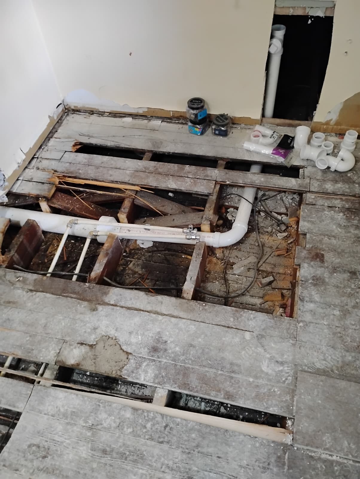 Drain and supply lines crossing the opened subfloor