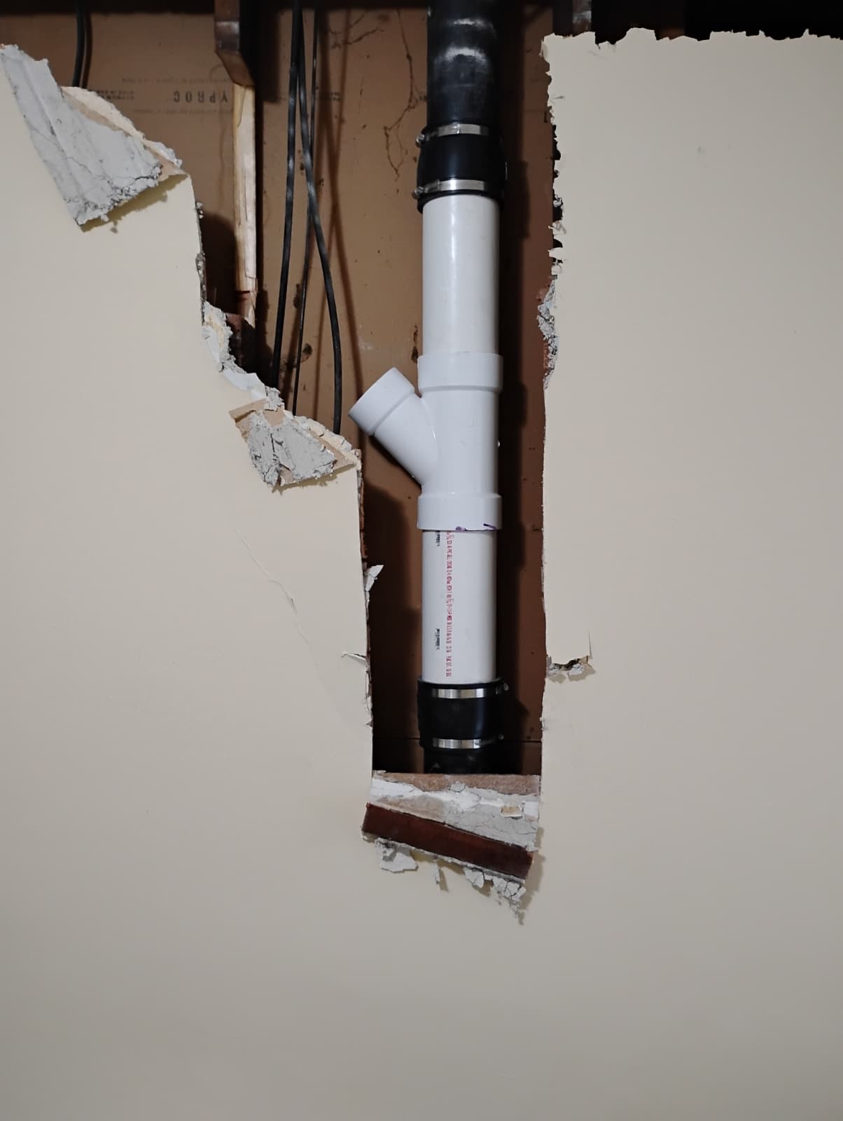 Vent and drain lines run through the opened wall
